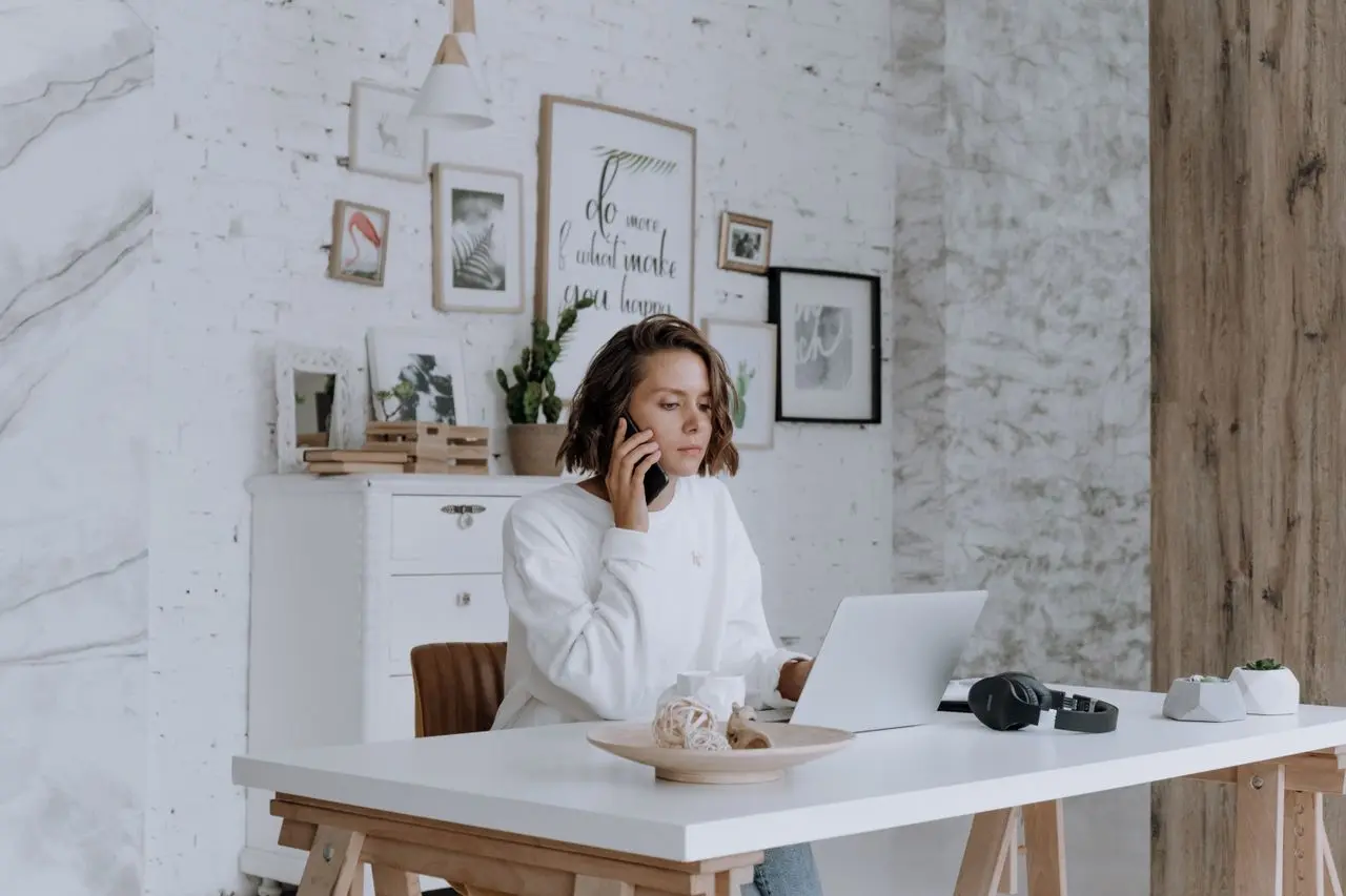 Personne concentrée passant un appel téléphonique devant son ordinateur portable pour négocier avec su banque (Photo sur Pexels)