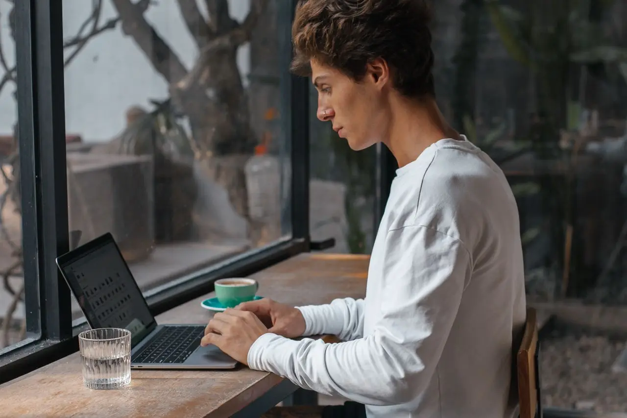 Professionista autonomo che lavora al computer in un bar mentre gestisce progetti e finanze