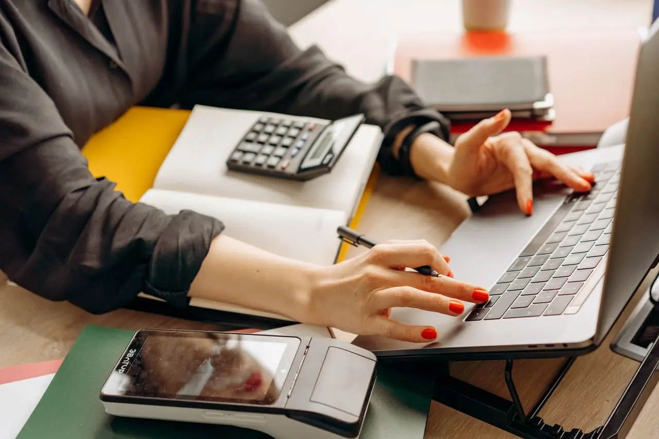Person analyzing budget and debt options with laptop and calculator at a desk (Photo on Pexels)