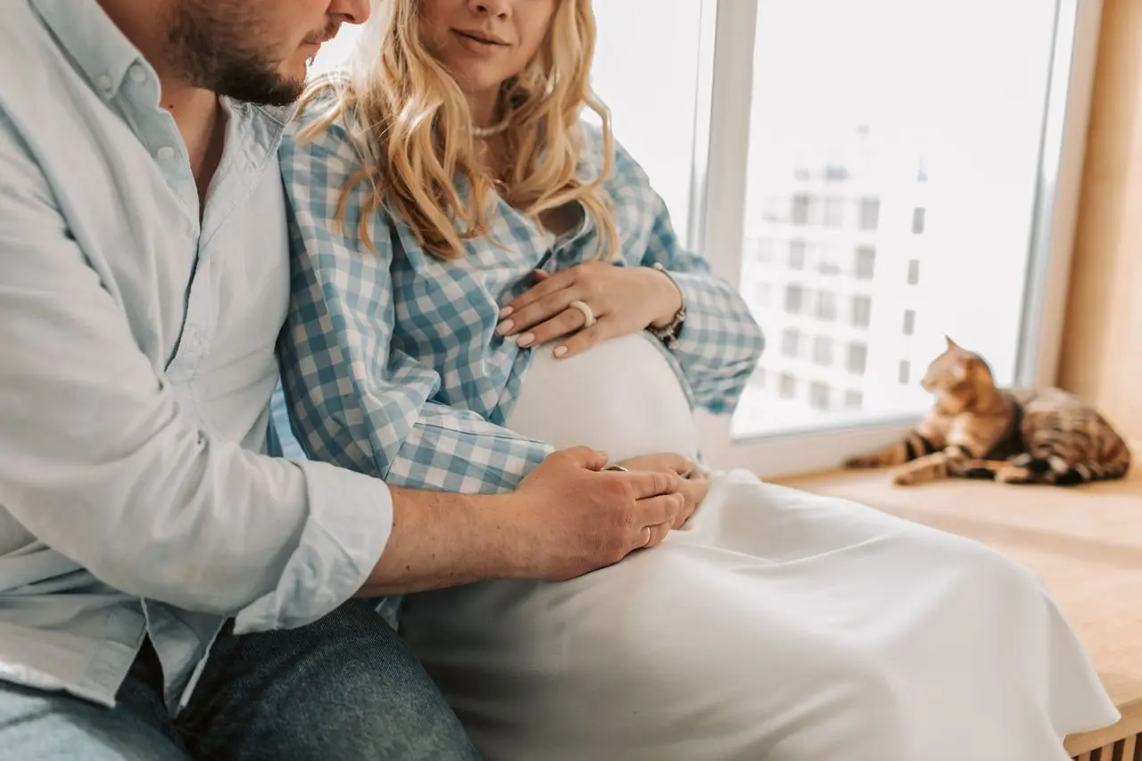 Coppia in attesa dell'arrivo del bambino in un ambiente domestico accogliente (Foto su Pexels)